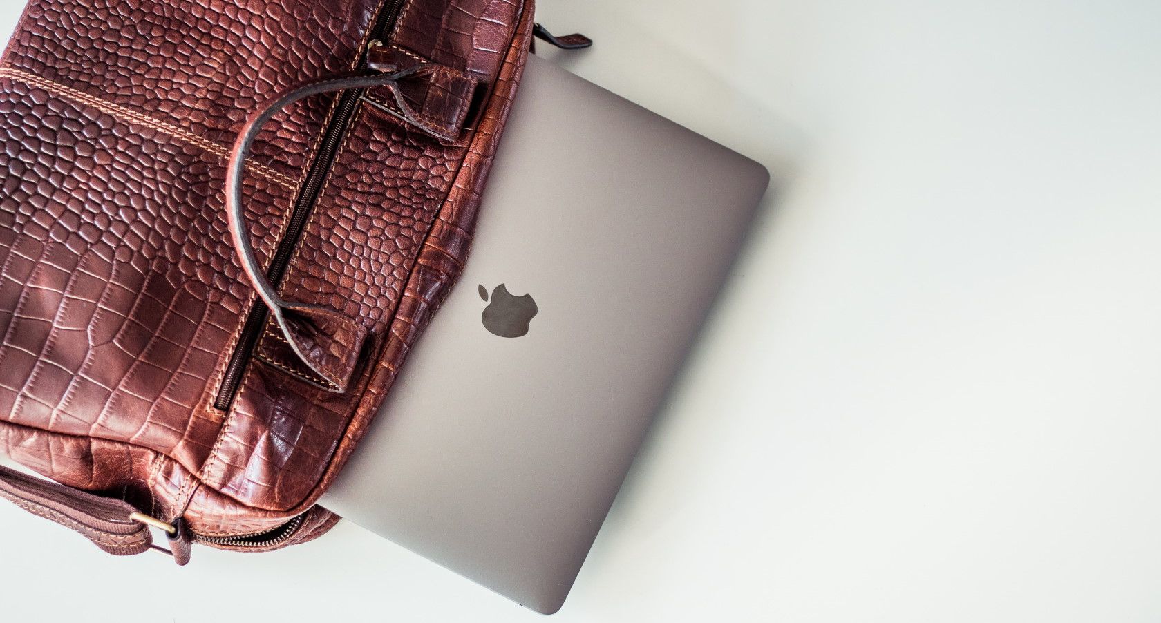 brown leather laptop bag on floor with laptop inside