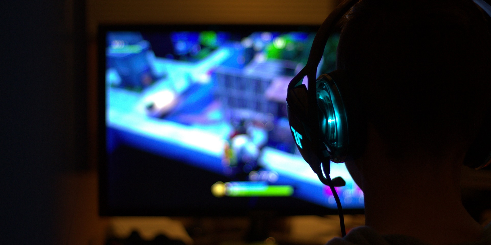 an image of a male playing fortnite on a monitor with a headset on