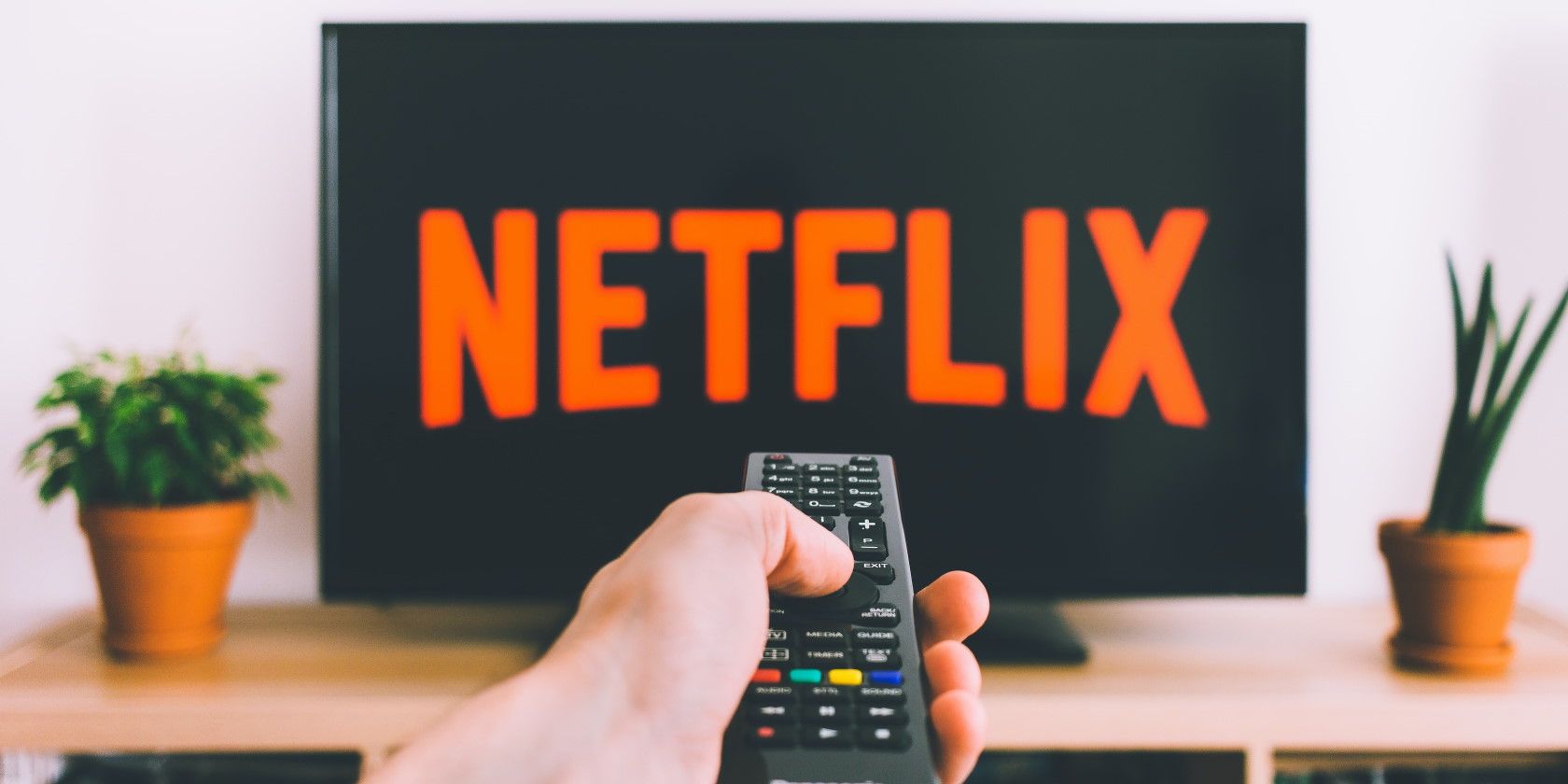 person holding remote and pointing in at TV showing Netflix streaming service