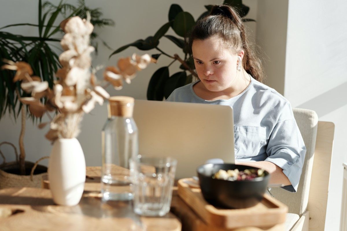A woman with Down's Syndrome sits in her home on a computer
