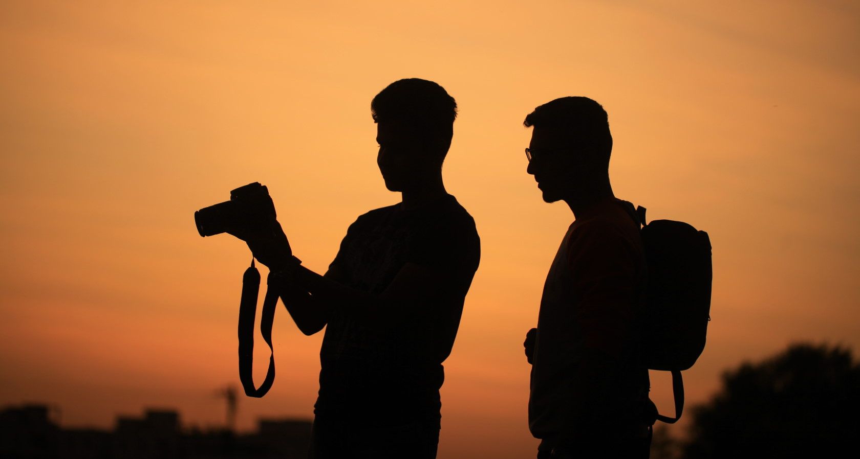 Silhouette of two photographers standing outside holding camera