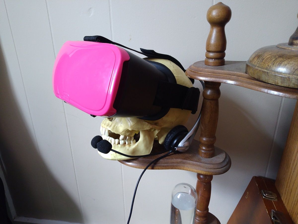 A VR headset on a skull with mic and headphones.