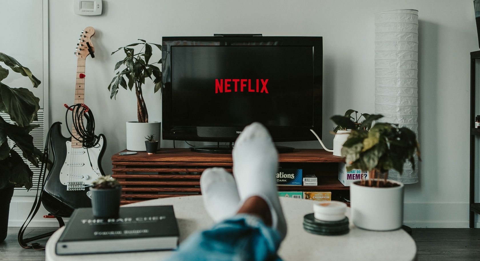 Pria dengan kaki di atas meja kopi menonton Netflix di TV