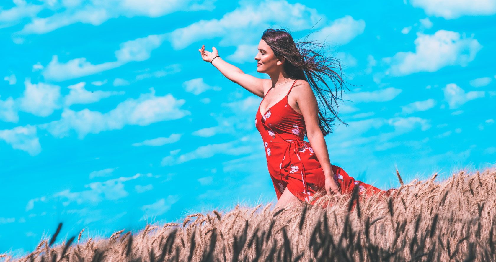 Woman walking through a field with wind blowing her hair