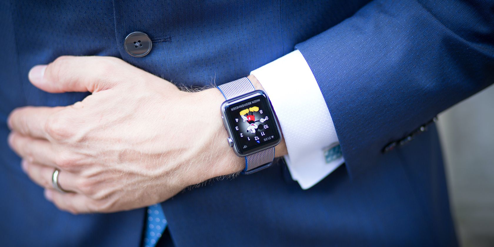 Pria Berpakaian Formal Mengenakan Apple Watch dengan Tampilan Jam Mickey Mouse