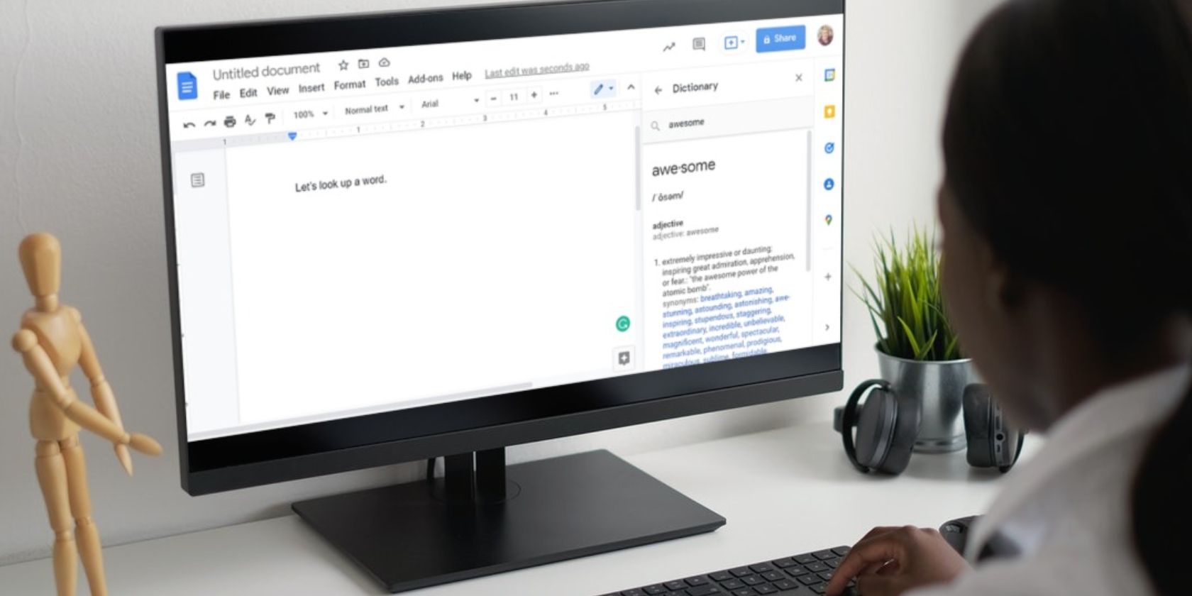 Image shows a woman using a desktop computer featuring the Google Docs dictionary tool