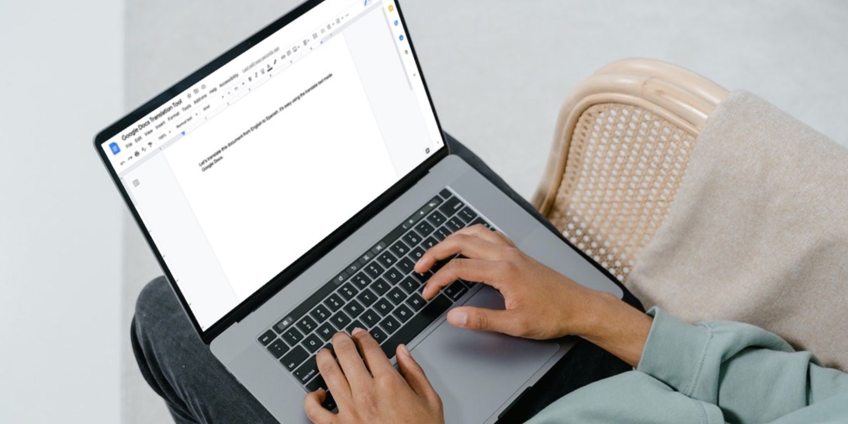 Image shows a man using a laptop to type in Google Docs
