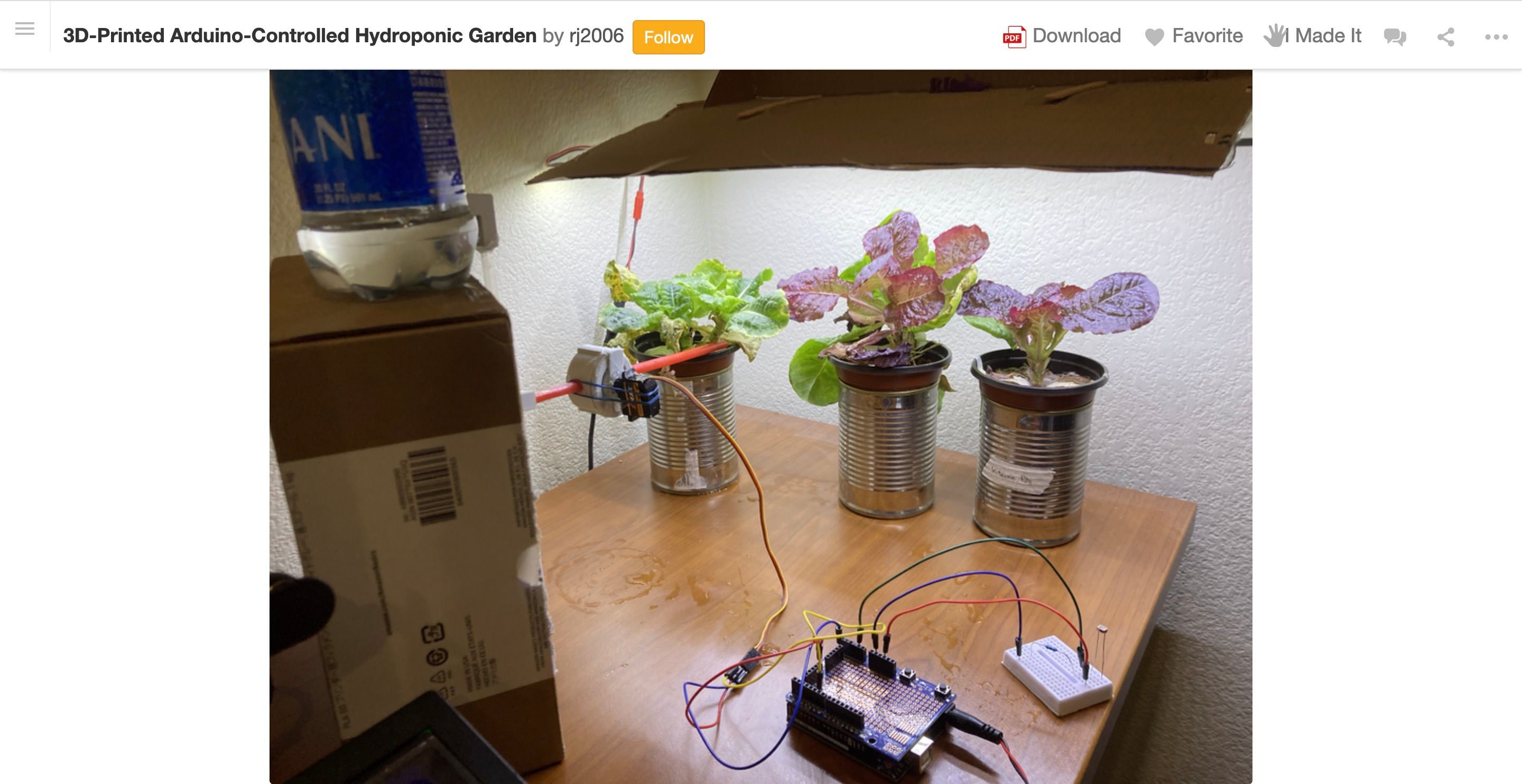 A table with three tin can pot plans with an arduino powering a watering system made from straws and 3D printed parts