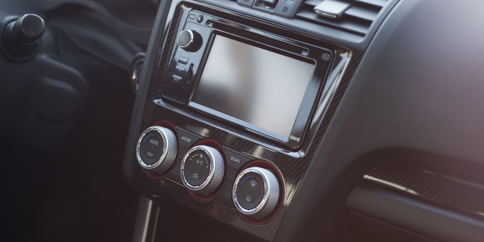Car dash showing infotainment unit and climate control knobs 
