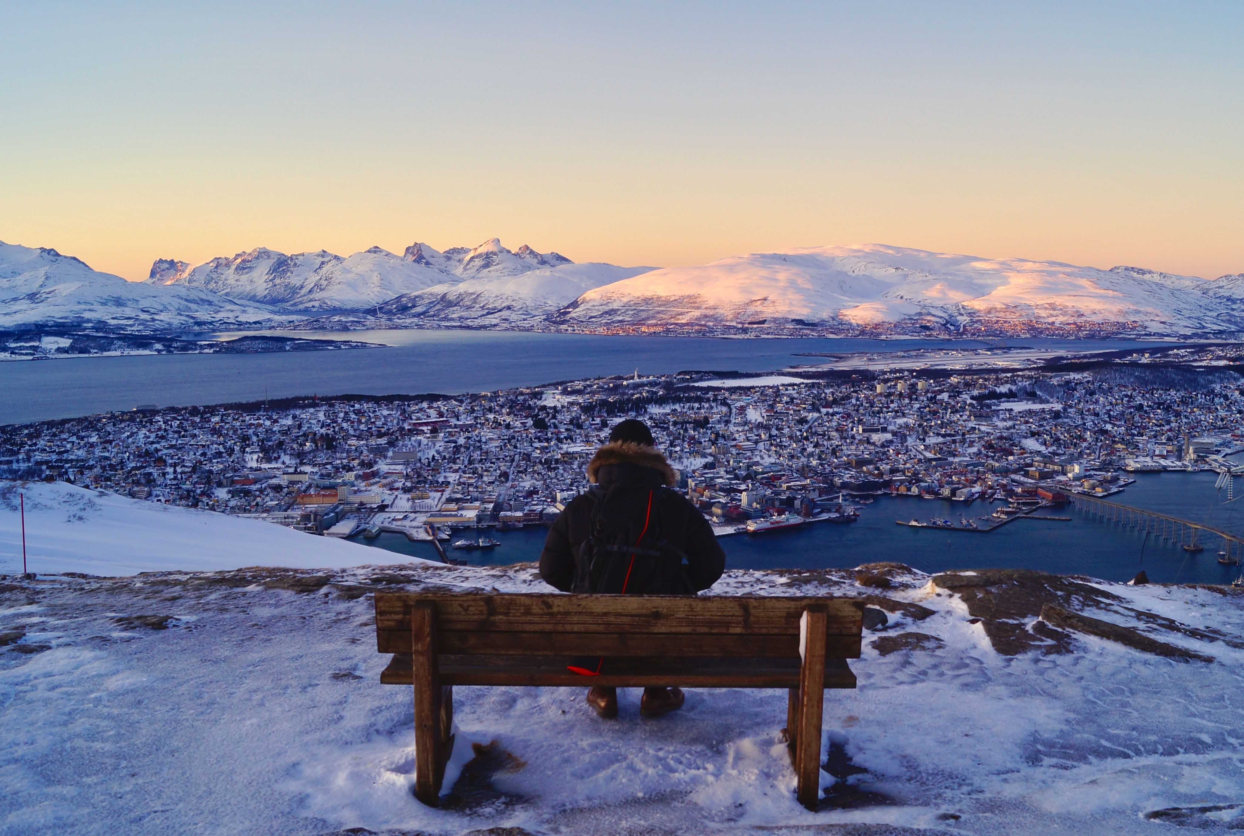 photo of a person sitting on a mountain overlooking a city