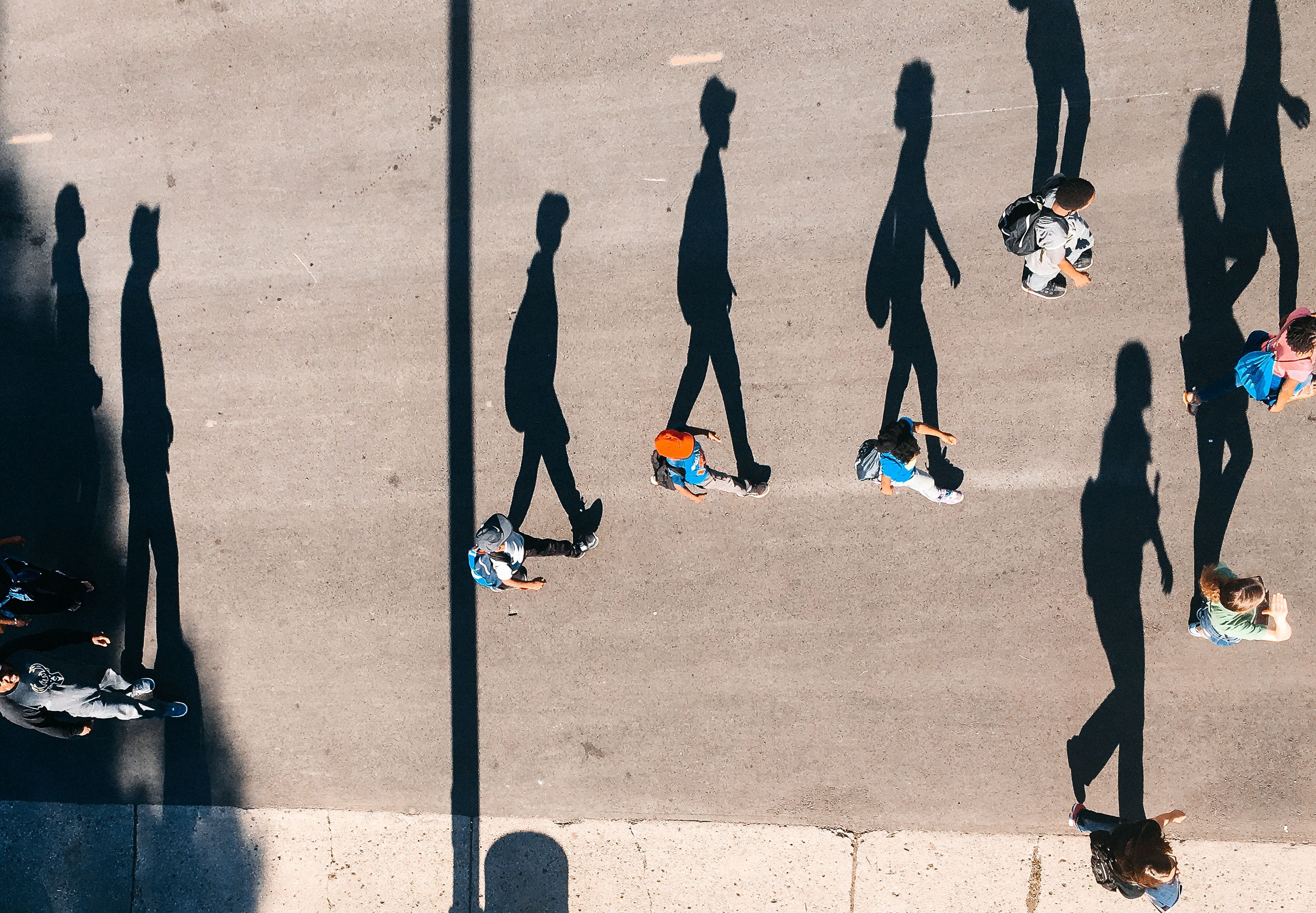 Photo of people walking with their shadows 
