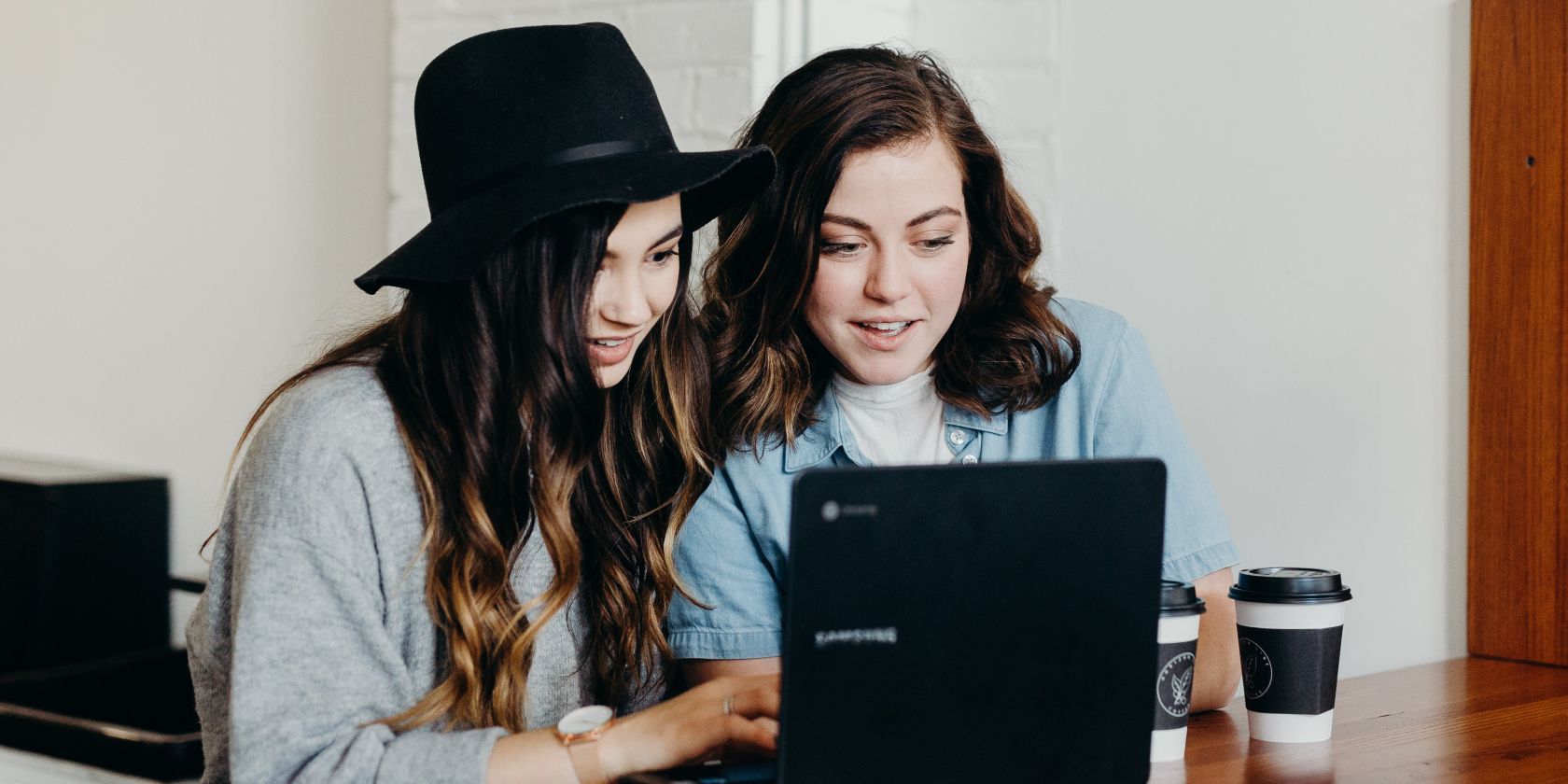 photo of two women sitting next to a computer on a desk