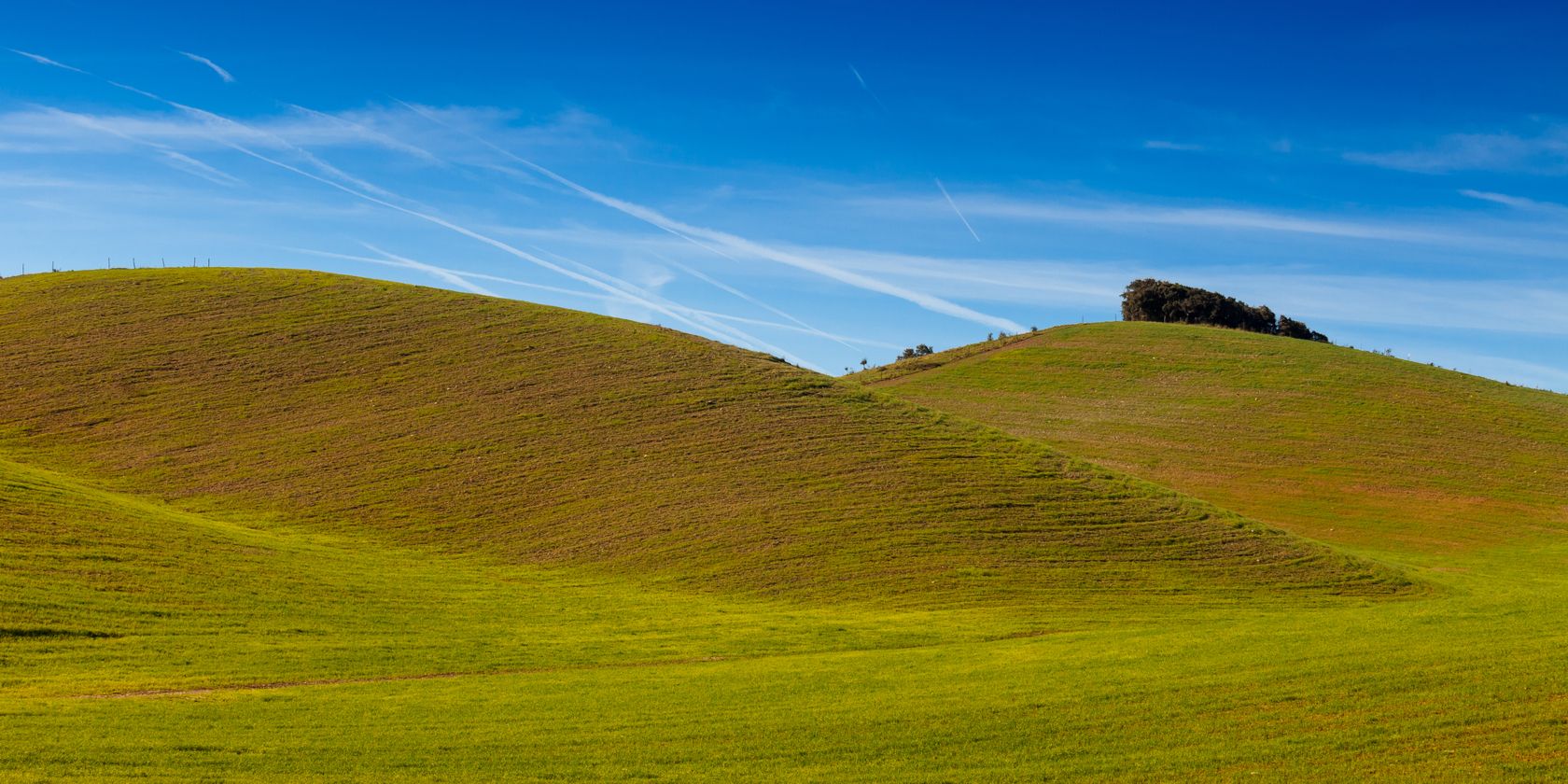 A brown grassy hill with a blue sky above