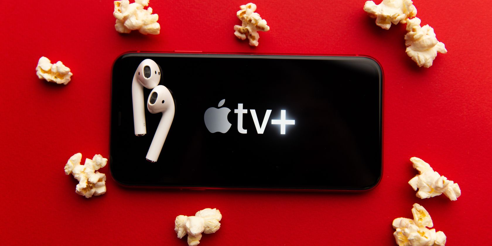 apple tv+ logo on mobile screen with popcorn and earbuds surrounding