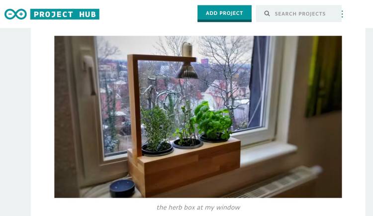 A screenshot showing a wooden desktop planter with an overhead light sitting on a windowsill
