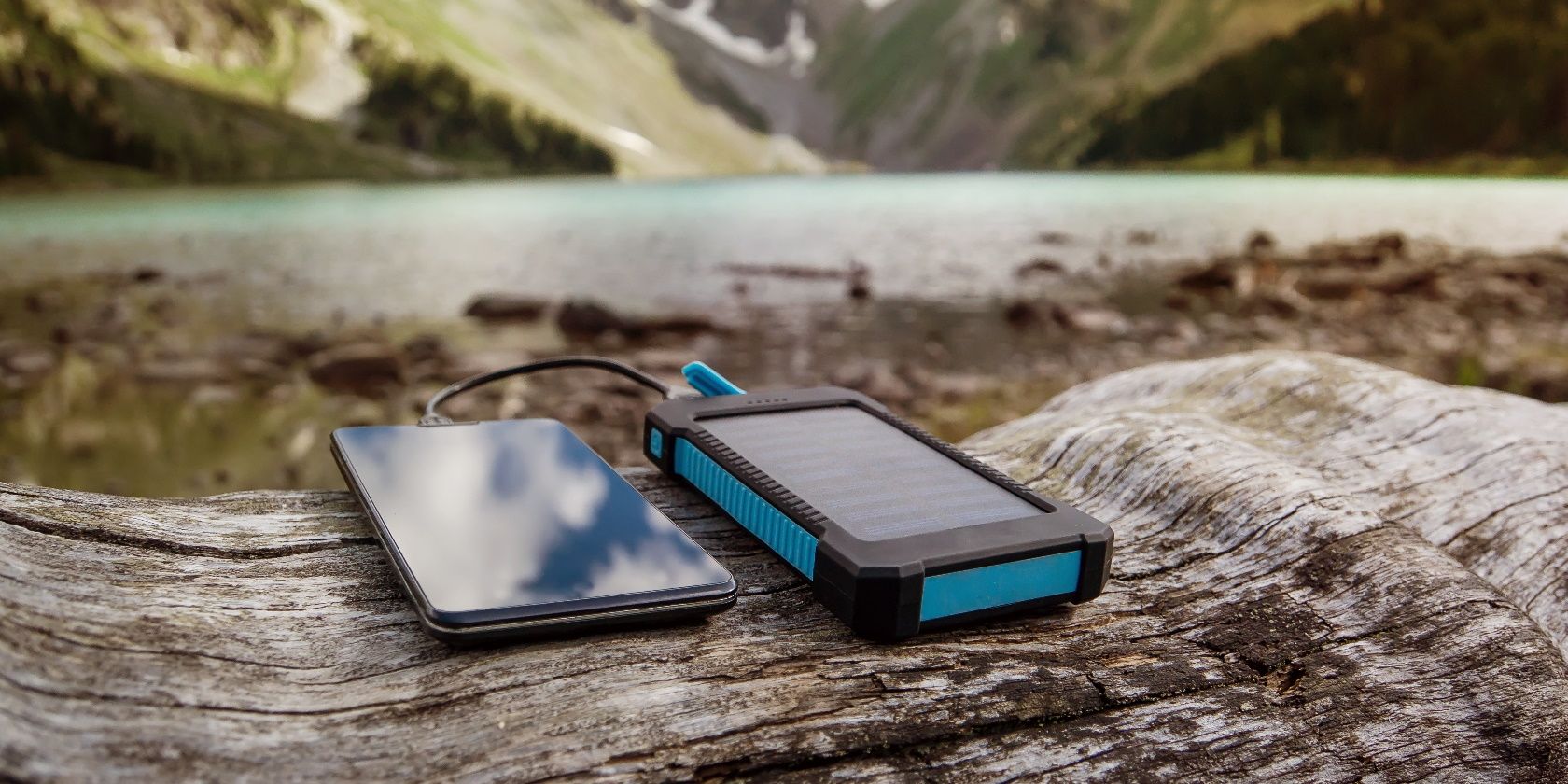 Battery solar energy device on the background of beautiful mountain scenery. Charge smart phone from the solar battery.