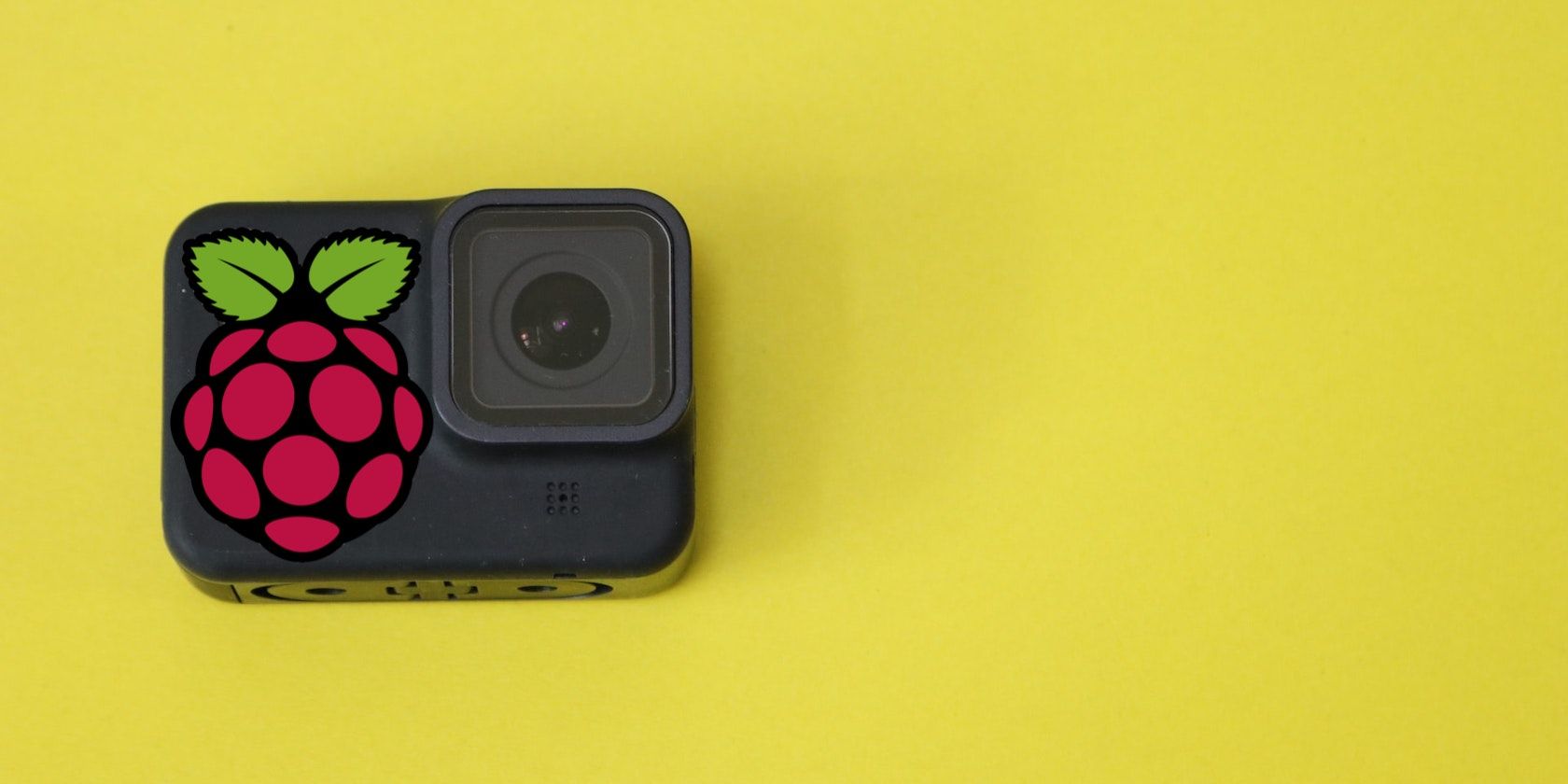 A small square camera with the Raspberry Pi logo on top set against a bright yellow background