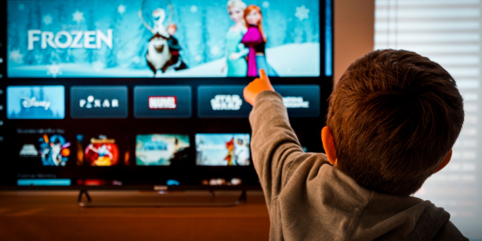 child pointing at disney+ on tv screen