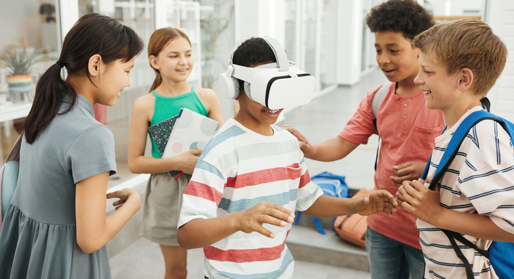 Group of children laughing and watching child wearing virtual reality headset