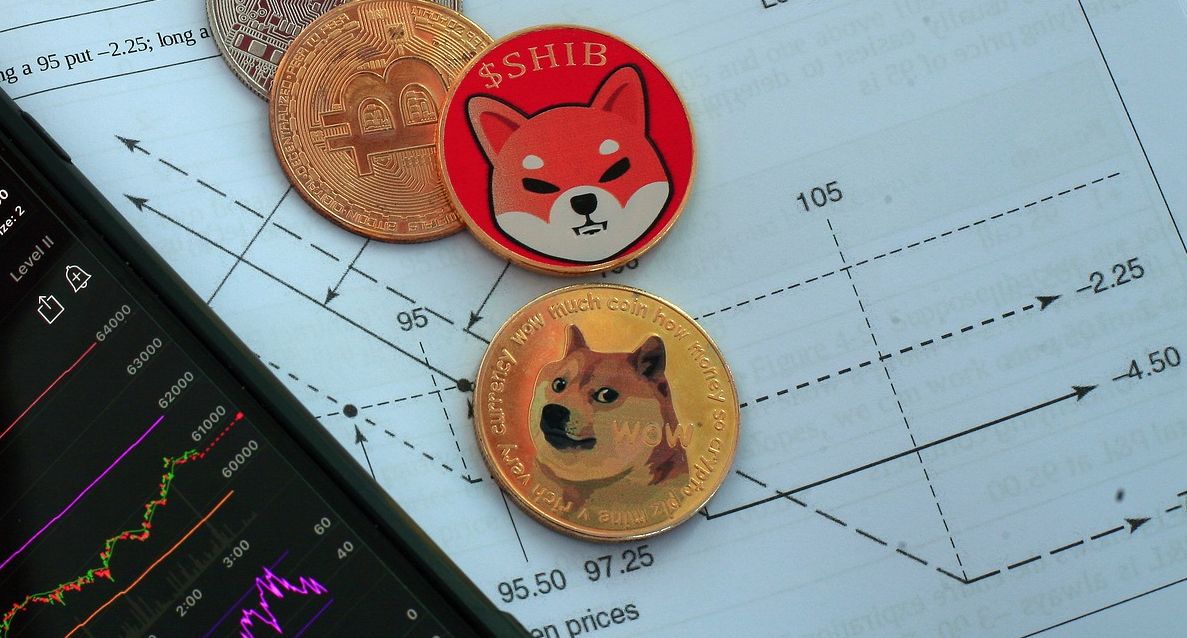 dogecoin and shiba inu coins on paper next to phone