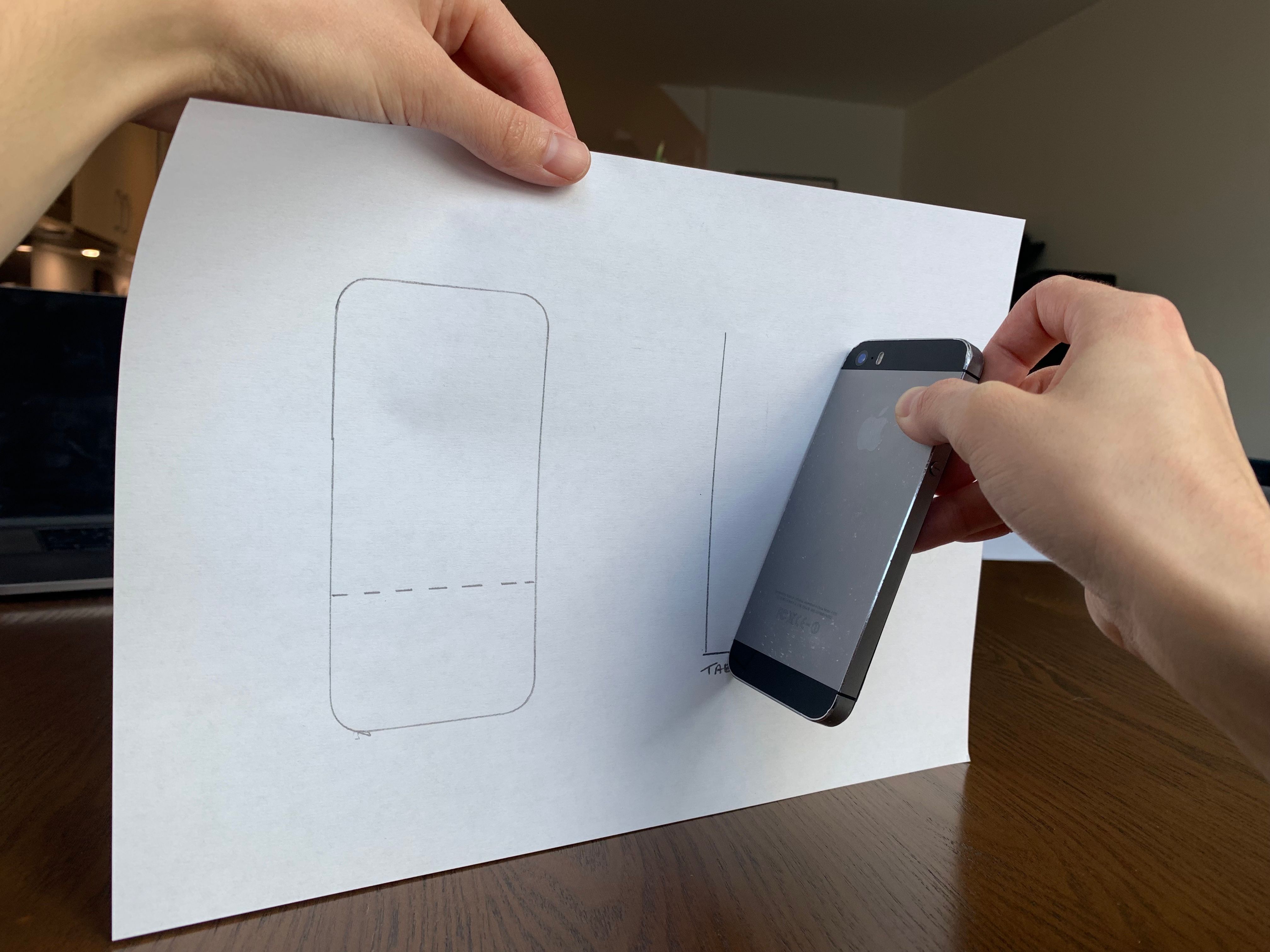 An iPhone held against a sheet of paper marking the angle