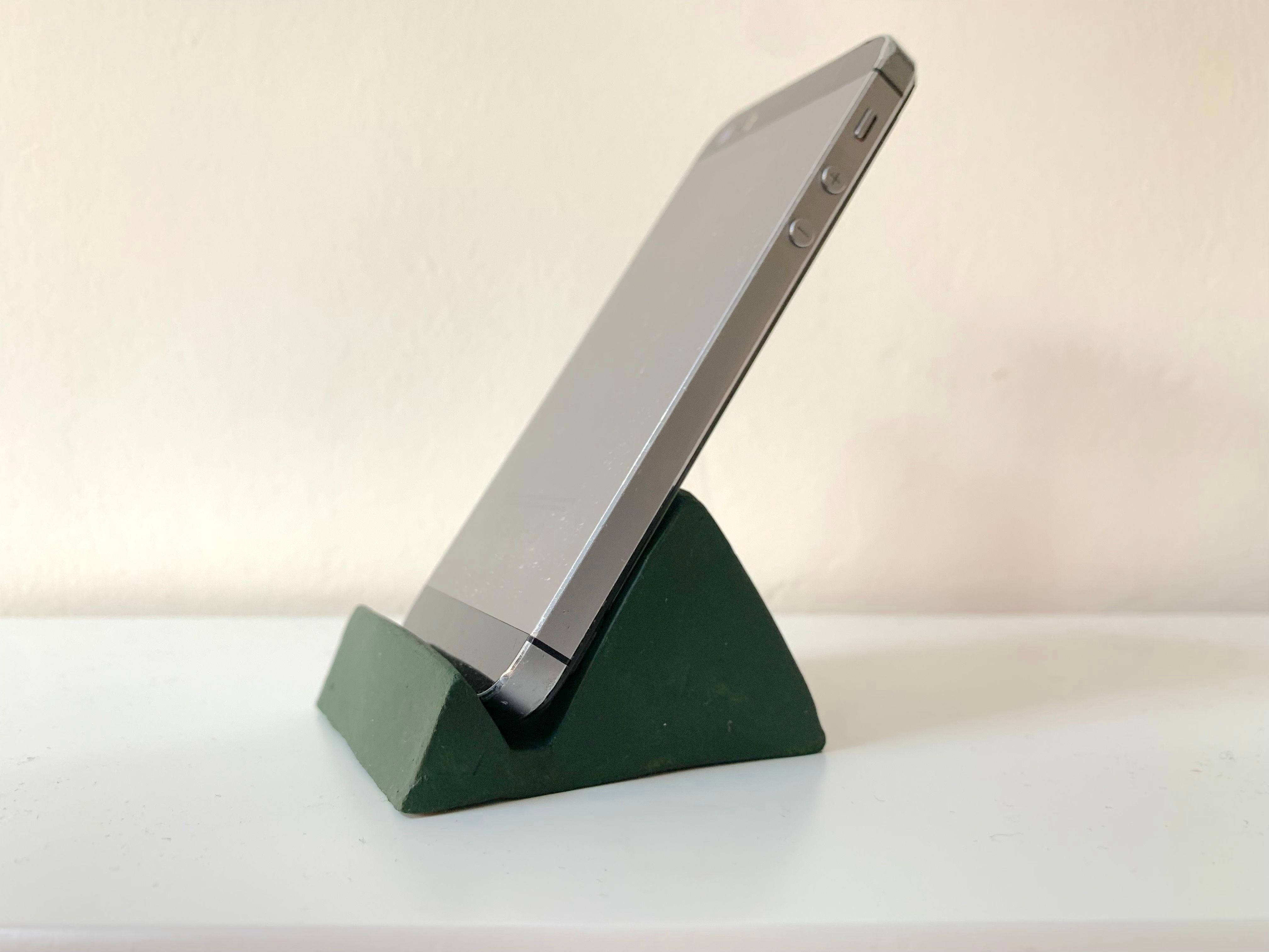 An iphone6s sitting in the finished clay phone stand painted green