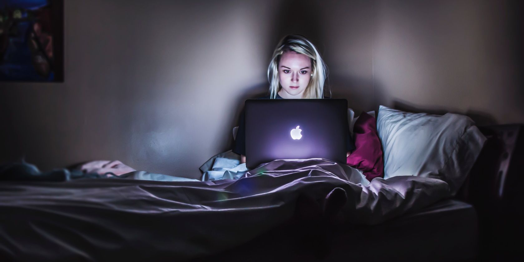 A woman using her laptop in a dark bedroom