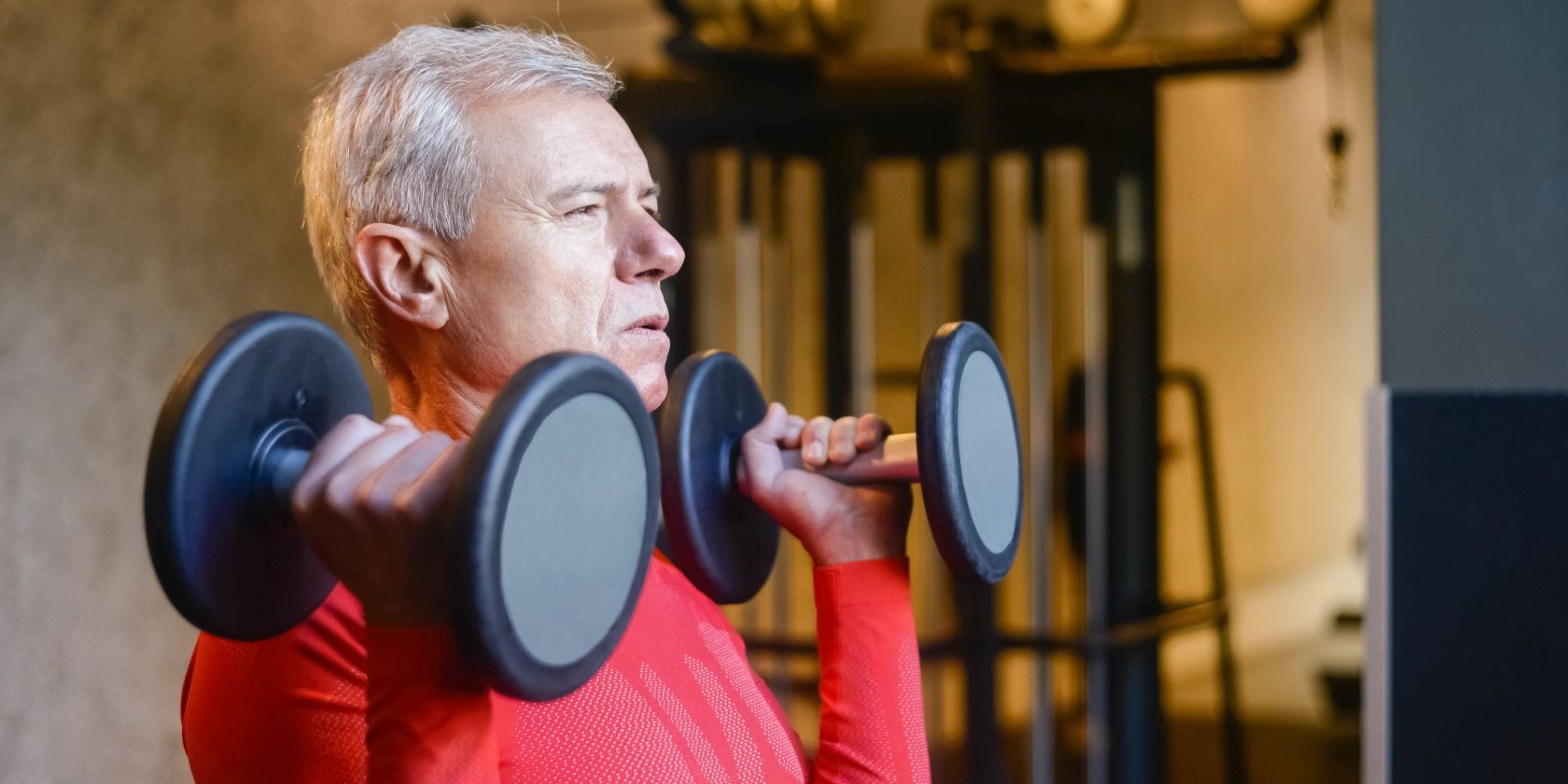 Senior man in gym and lifting up dumbbells