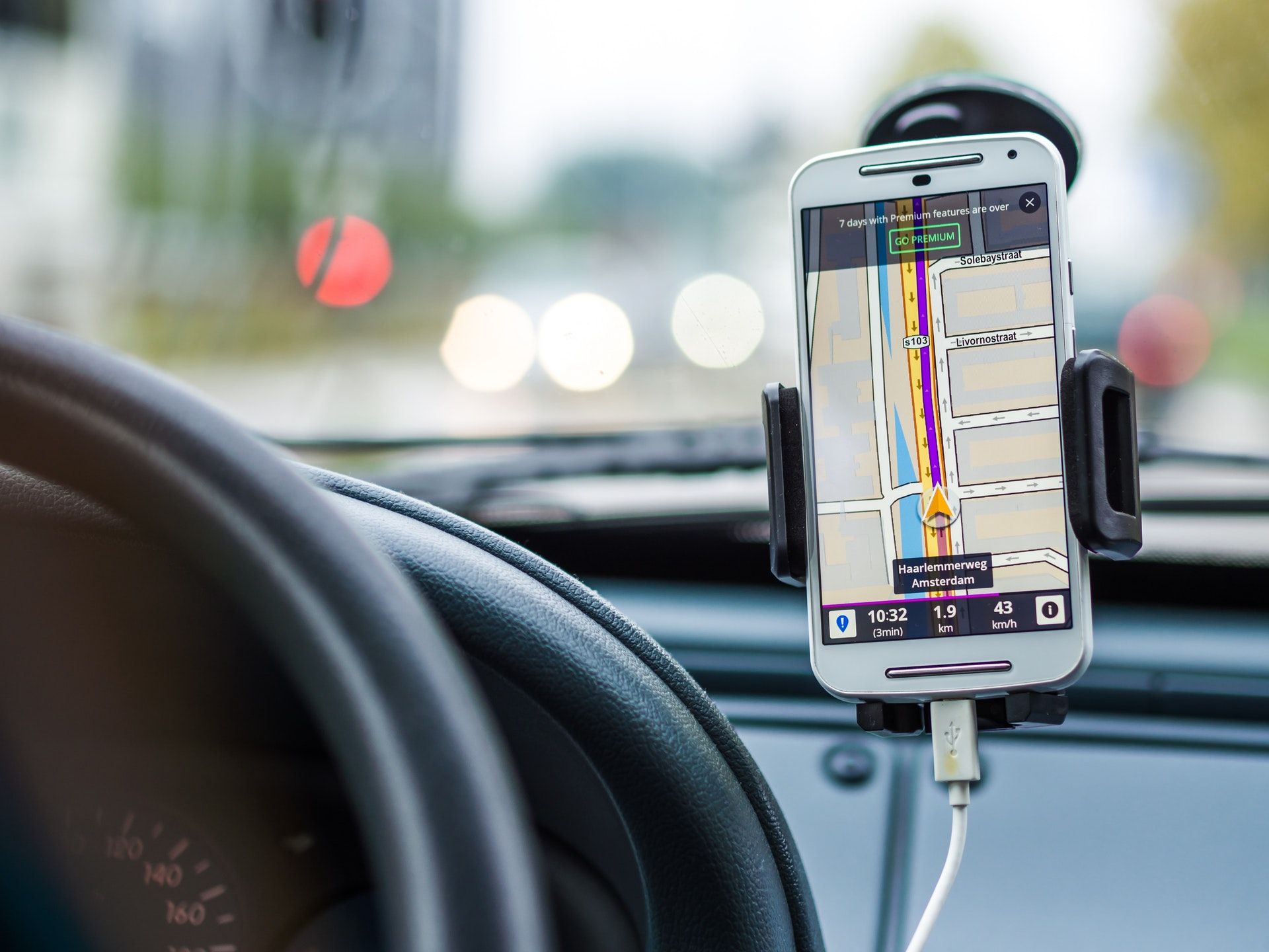 smartphone mounted with charging cable showing navigation in car