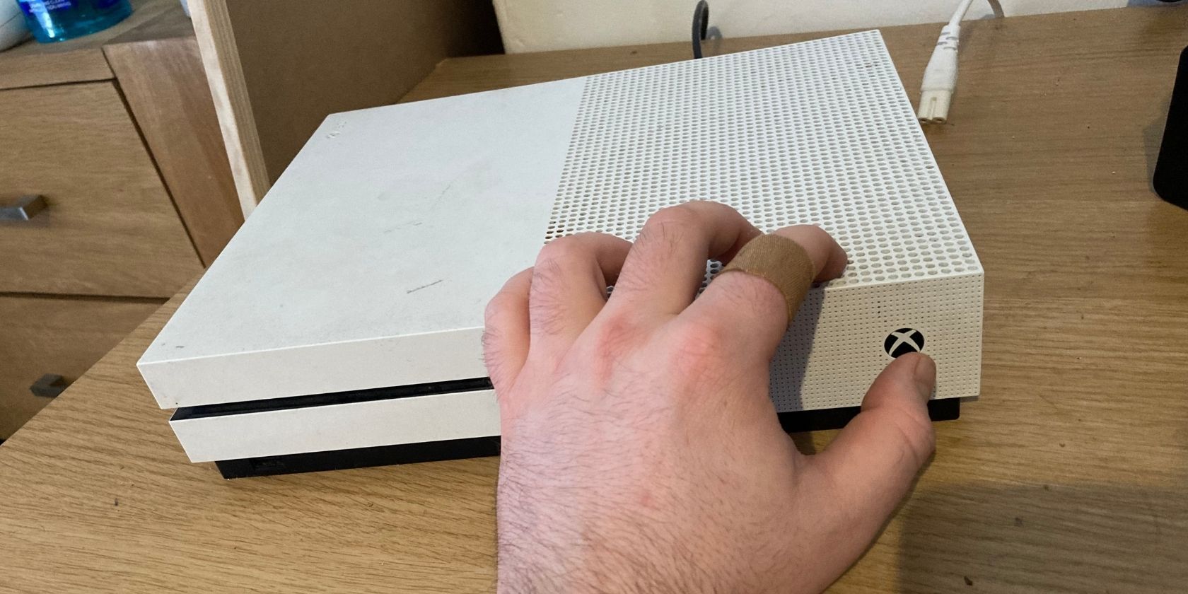 A disconnected Xbox One about to have its Power button pressed.