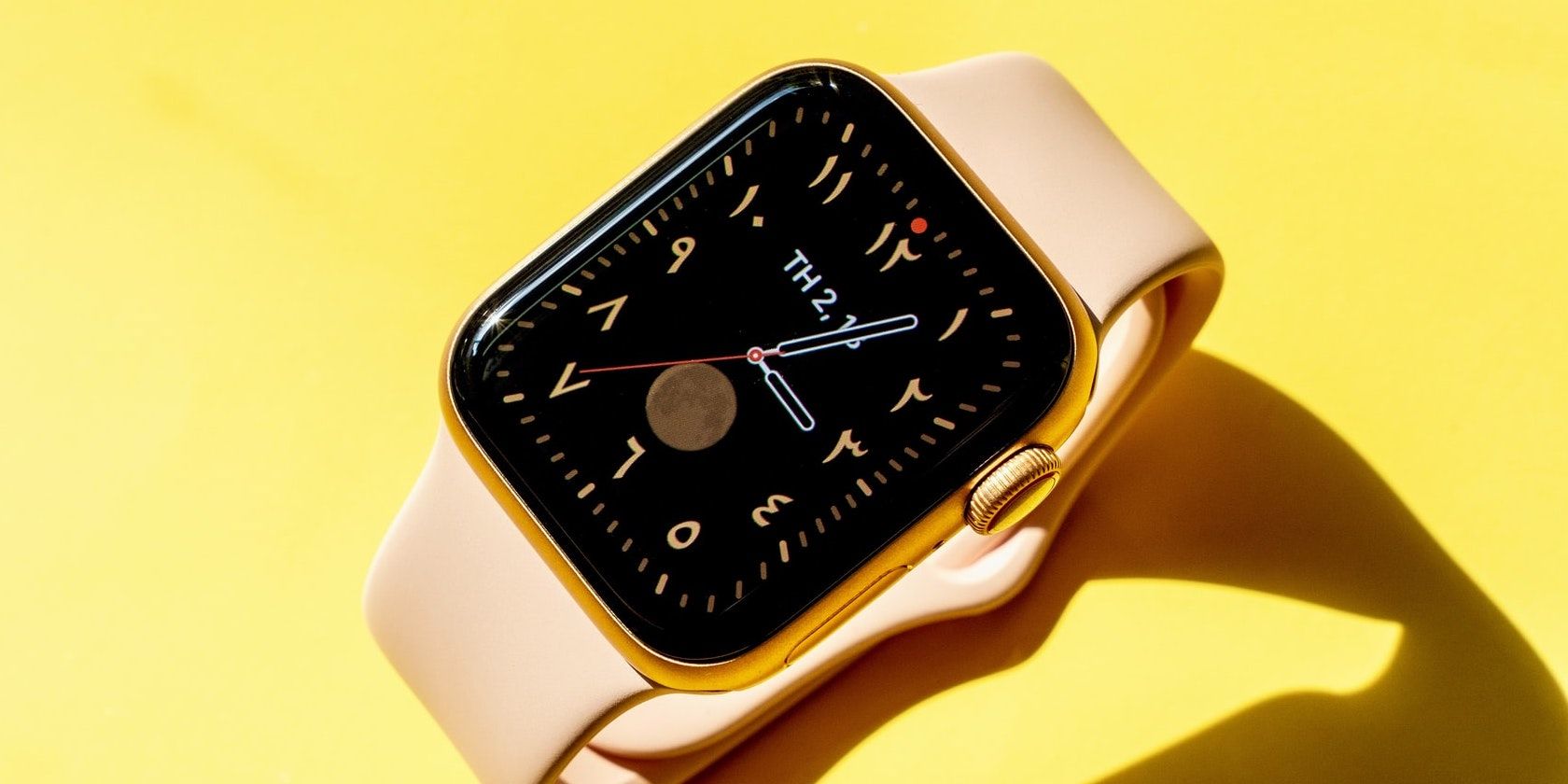 Apple watch on a yellow background showing the watch face