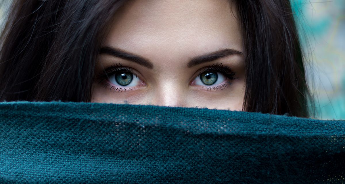 Close up of a woman's face showing blue eyes with a blanket covering the lower half.