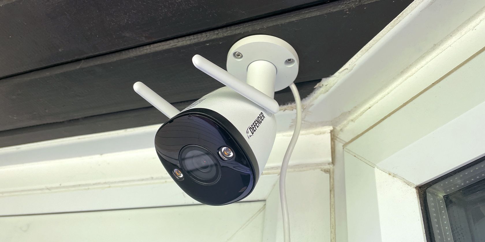 Defender Guard Pro 2K Wi-Fi Security Camera on Black Wooden Porch