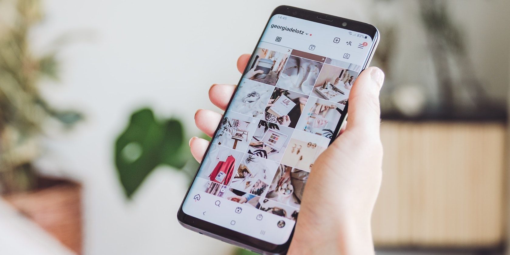 a hand holding a phone, the user is browsing Instagram