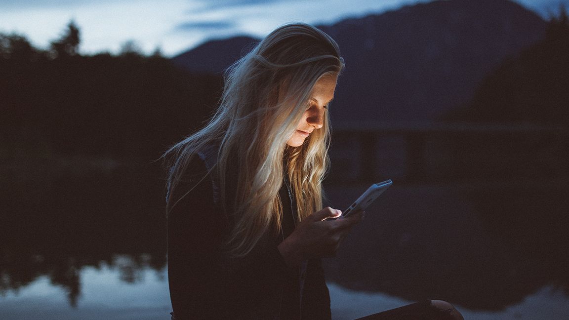 Woman using phone outdoors at night
