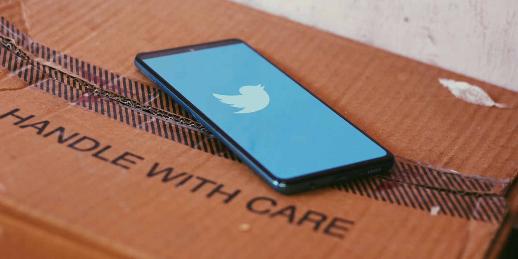 Twitter on smartphone placed on box that reads Handle With Care