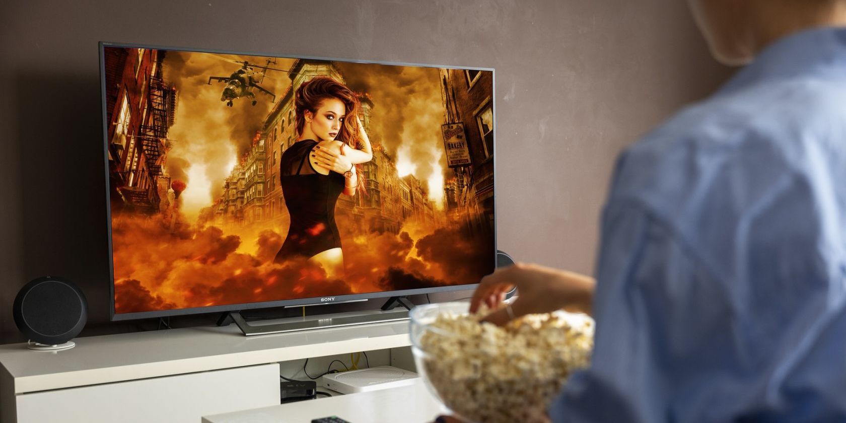 Woman watching action movie on TV while eating popcorn