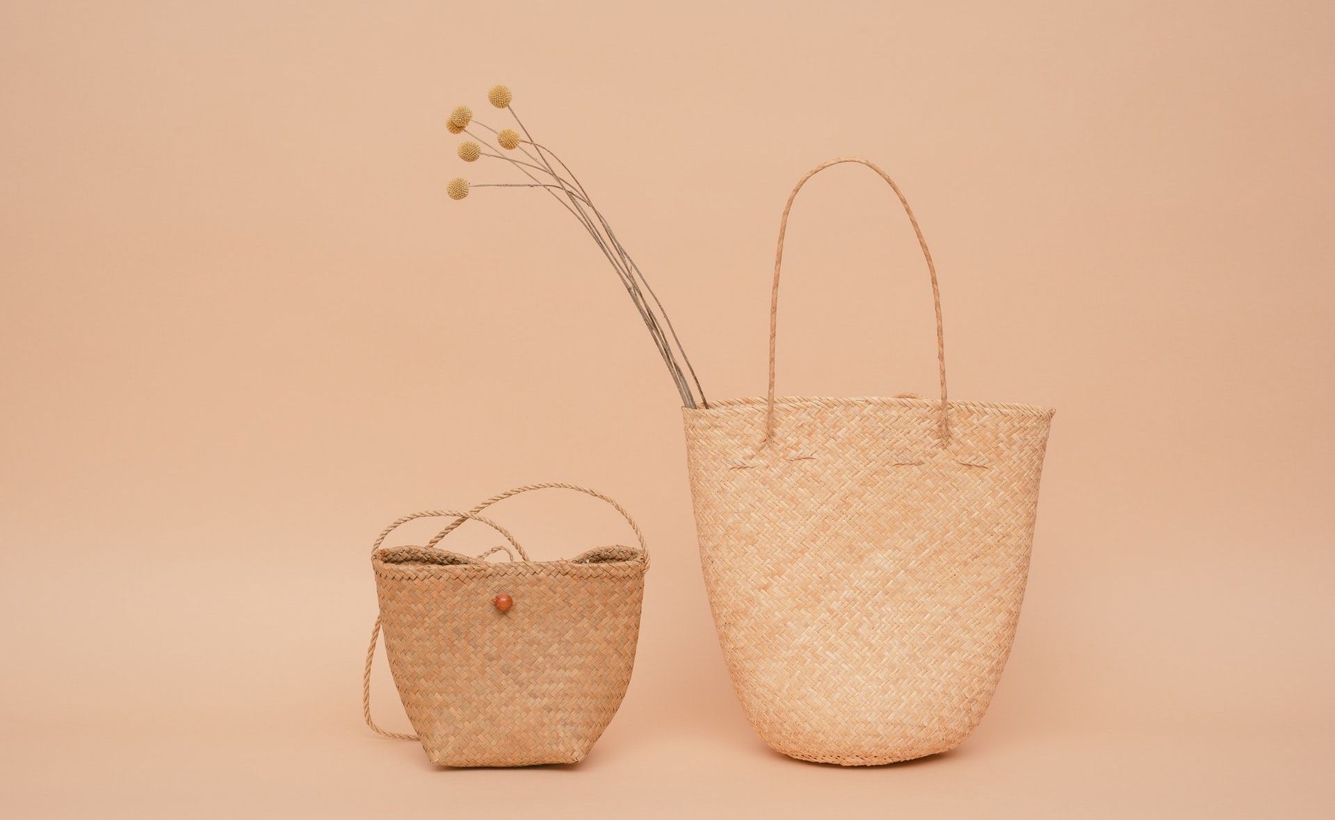 A photo of two woven flax baskest against a pink background