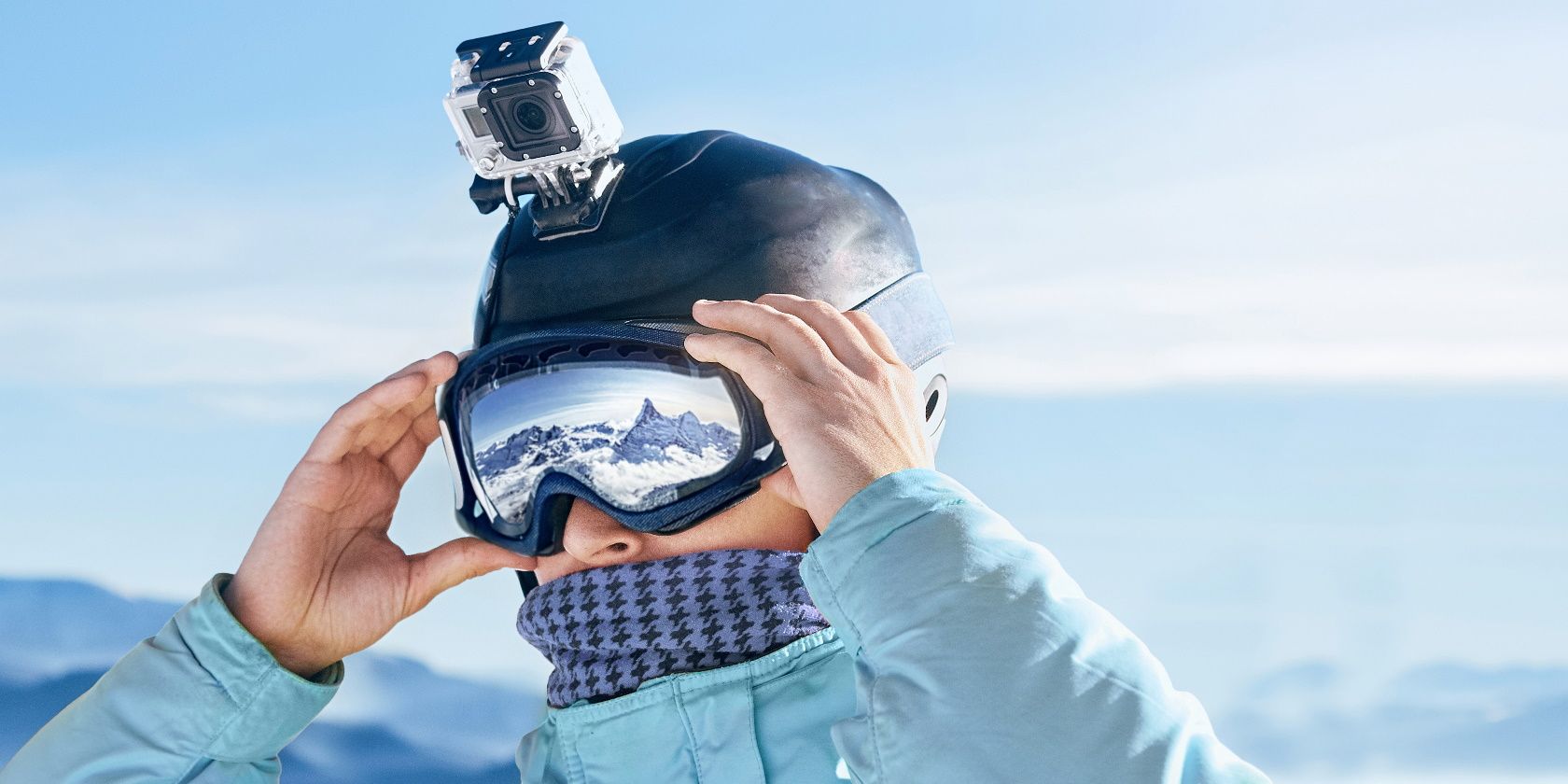 Skier with action camera on a helmet. Ski goggles with the reflection of snowed mountains