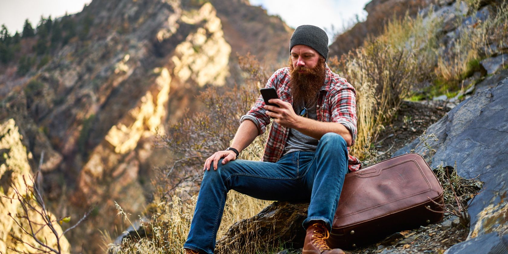 bearded guy lost in the mountains looking on phone for directions