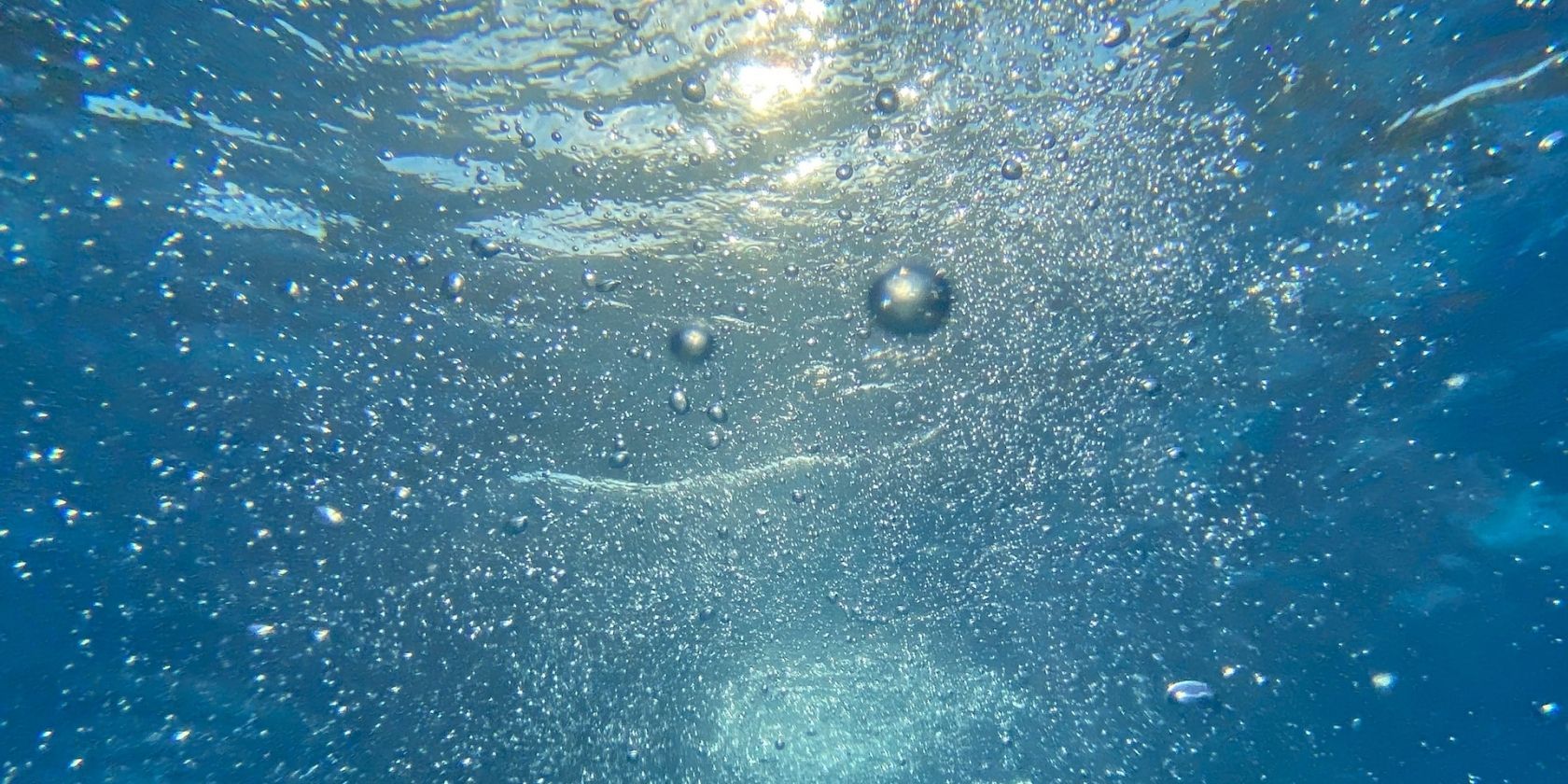 blue underwater image with lots of small bubbles