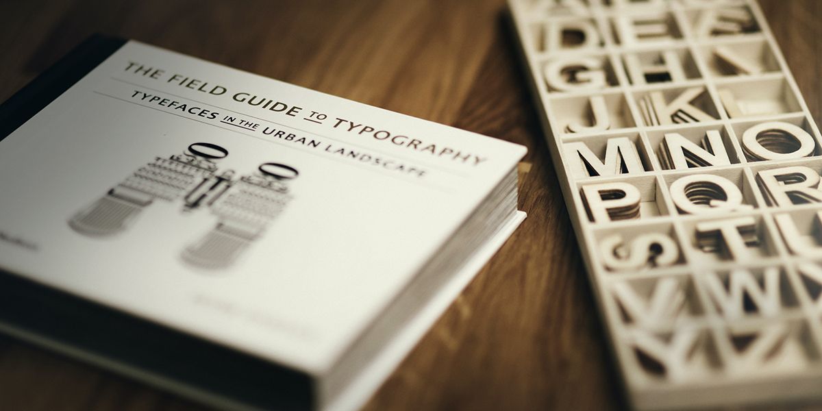 A book titled "The field guide to typography" next to a book of wooden letters.