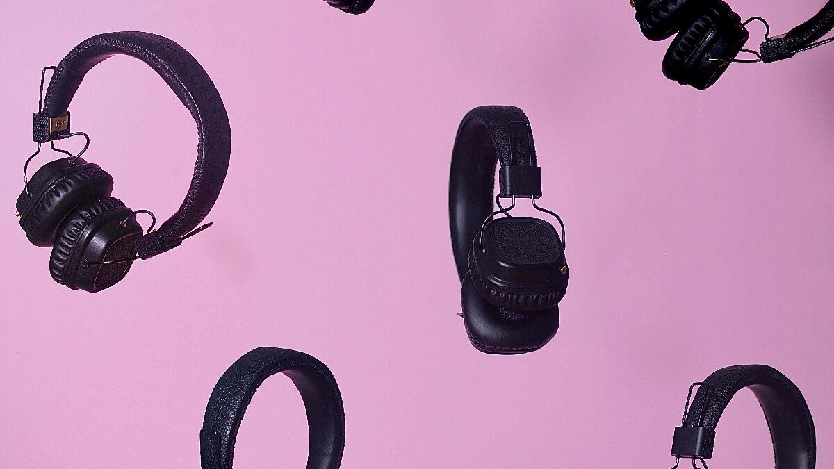 multiple black headphones on a pink background. 