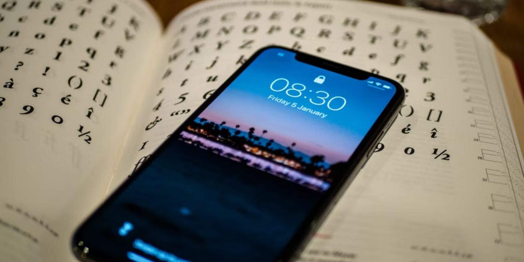 iPhone showing Lock Screen placed on book showing numbers and letters