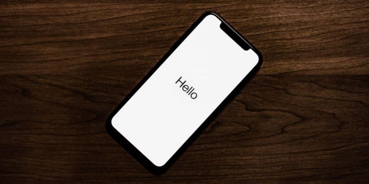 iphone on wooden surface showing hello welcome screen 