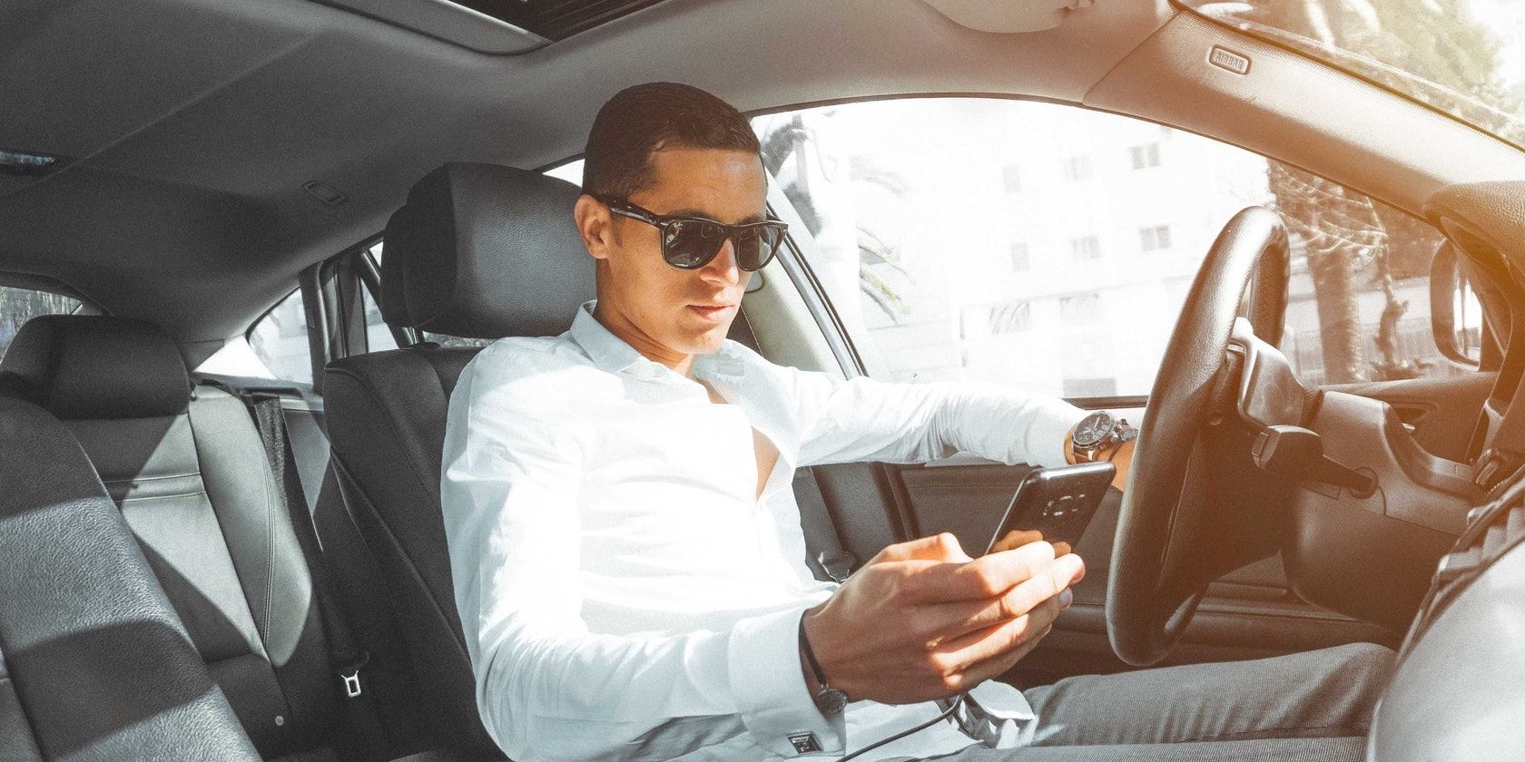 Man holding phone in car 
