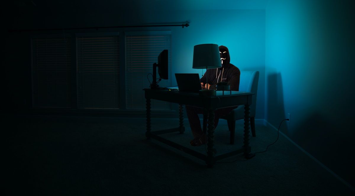 A man using his computer disguised as a hacker.
