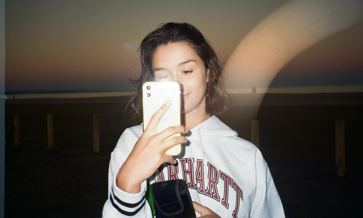 Vintage style photo of a girl holding her phone camera with flash on.