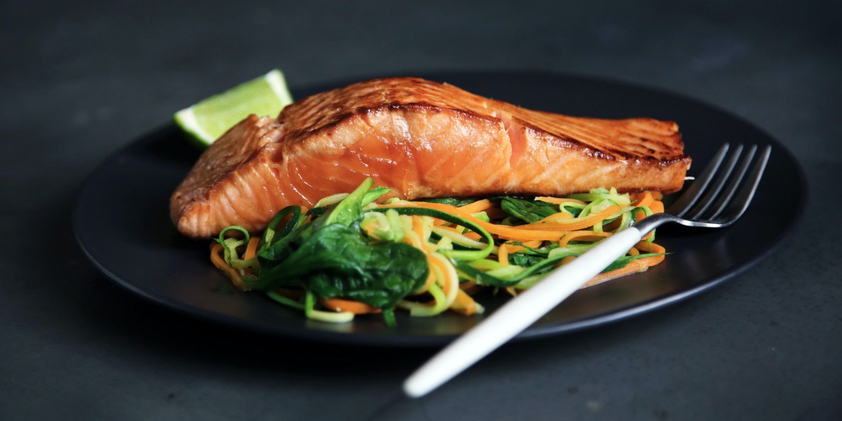 Close-up of cooked salmon and salad on black plate