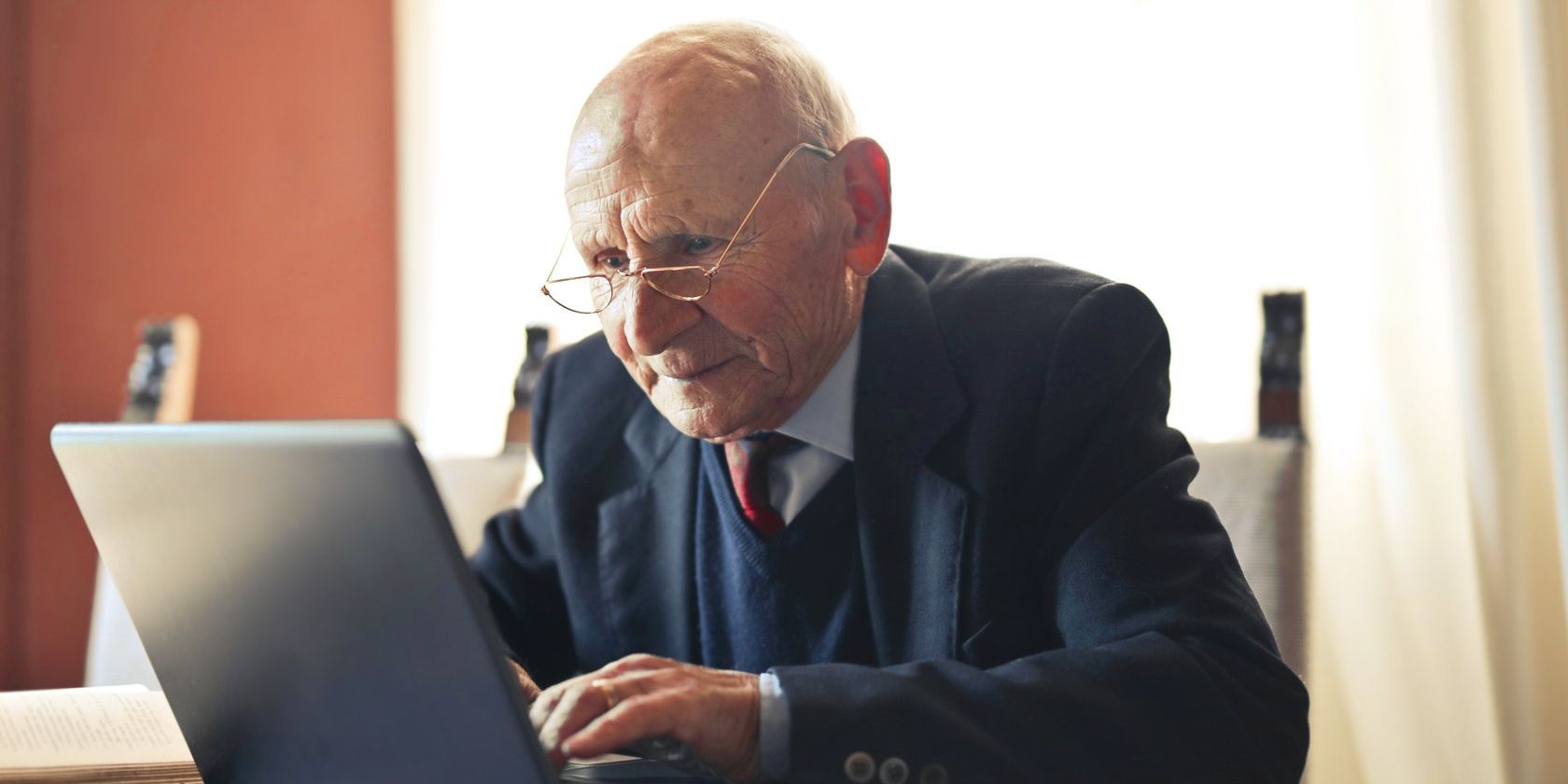 serious senior man in formal suit working on laptop at workplace